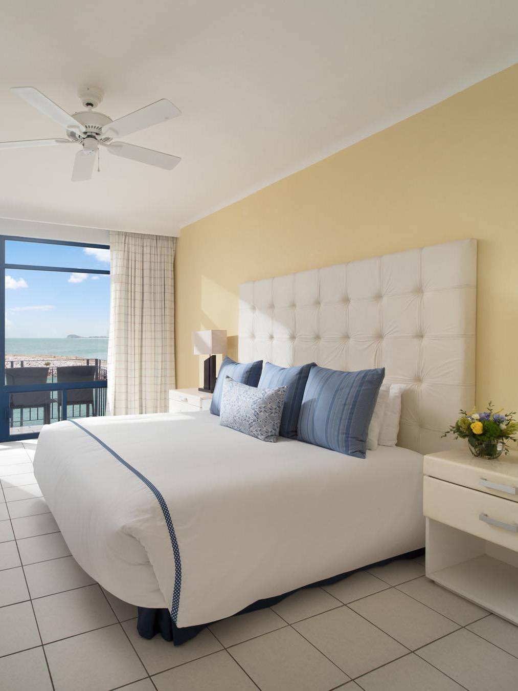 King bed with white sheets and view of sky from window