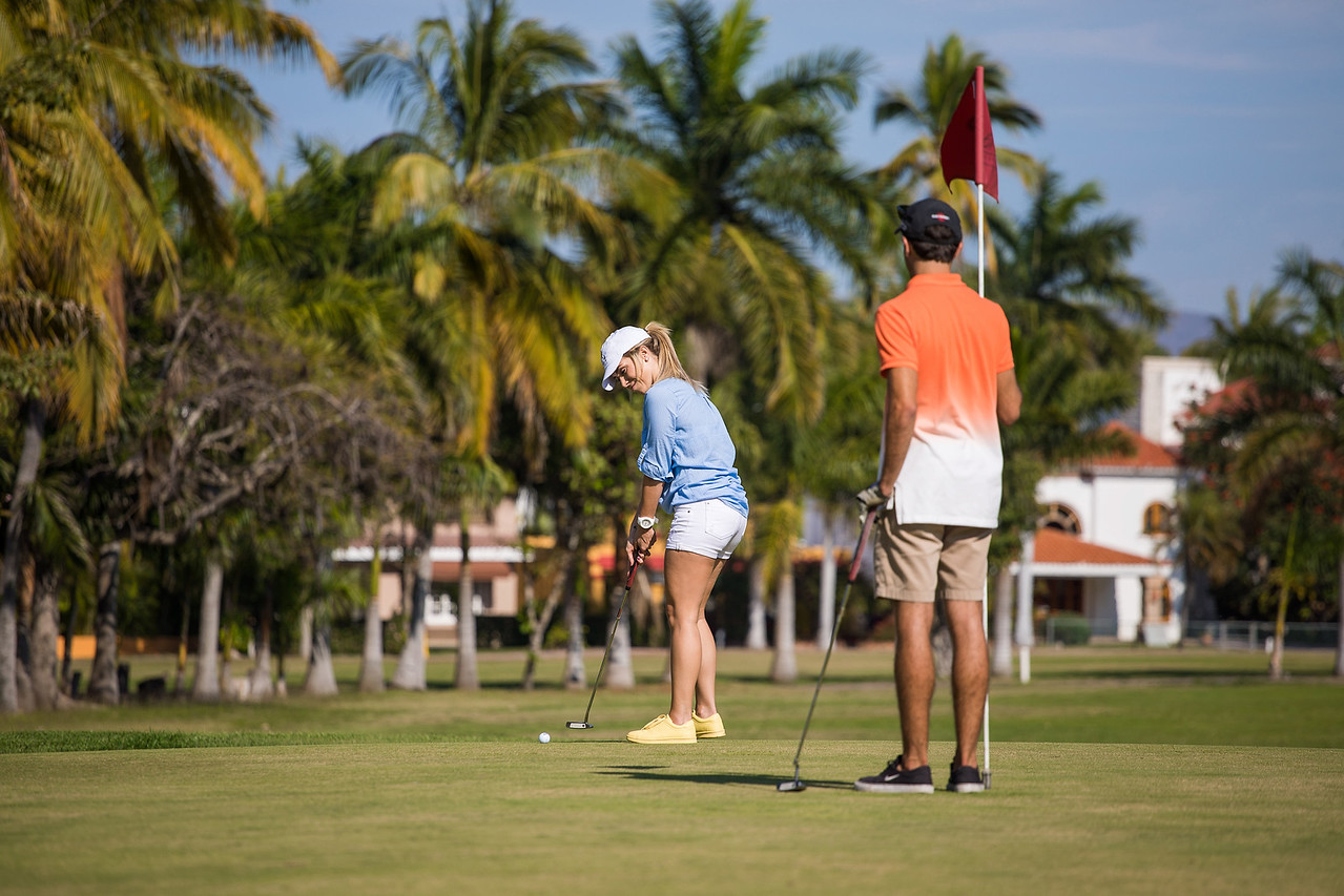 Three men smiling with golf clubs